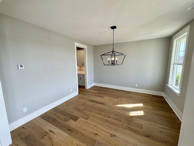 unfurnished dining area featuring a chandelier and hardwood / wood-style flooring