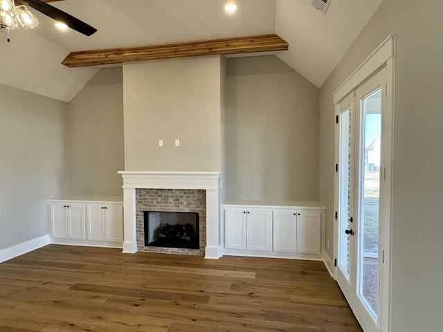 unfurnished living room with ceiling fan, dark hardwood / wood-style flooring, a brick fireplace, and vaulted ceiling with beams