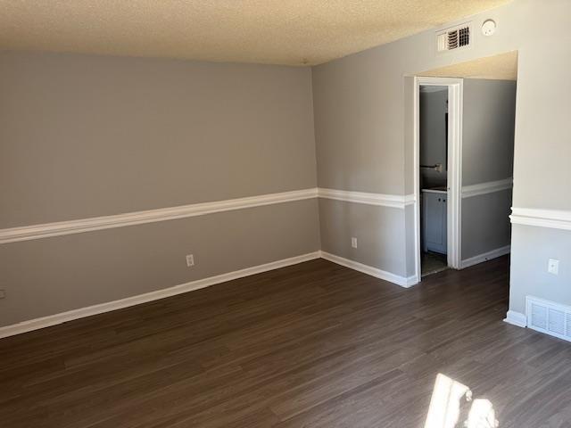 unfurnished room with a textured ceiling and dark hardwood / wood-style floors