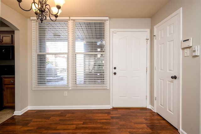 entrance foyer with dark hardwood / wood-style flooring and a notable chandelier