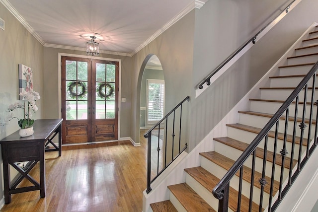 entrance foyer with french doors, ornamental molding, and light hardwood / wood-style floors