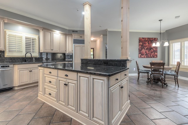 kitchen with sink, dark stone counters, hanging light fixtures, a kitchen island, and a notable chandelier