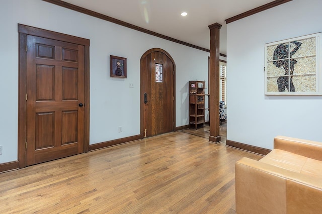 foyer entrance with ornate columns, crown molding, and light hardwood / wood-style flooring