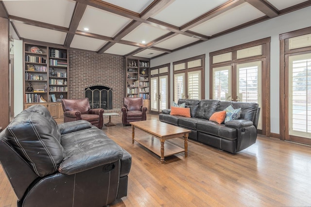 living room with coffered ceiling, light wood-type flooring, a fireplace, built in features, and beamed ceiling