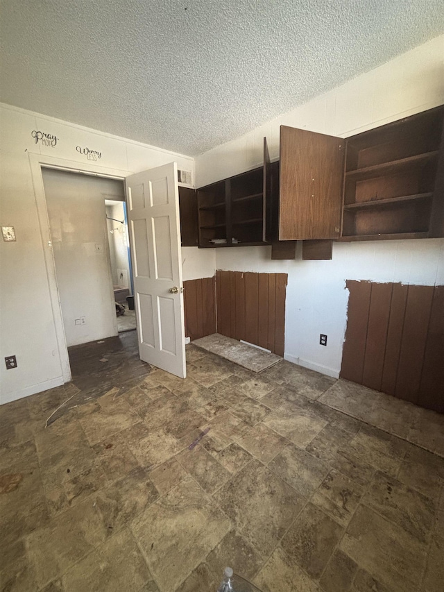 kitchen featuring a textured ceiling and dark brown cabinetry