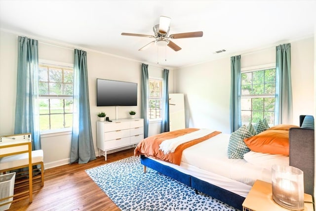 bedroom featuring multiple windows, ceiling fan, ornamental molding, and light hardwood / wood-style flooring