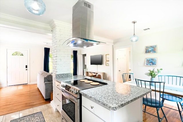 kitchen with decorative light fixtures, white cabinets, a kitchen bar, stainless steel electric range, and island range hood