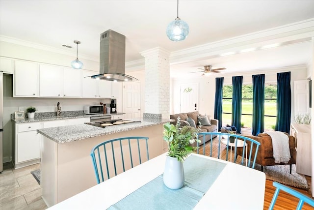 kitchen featuring island exhaust hood, ceiling fan, white cabinets, decorative light fixtures, and decorative columns