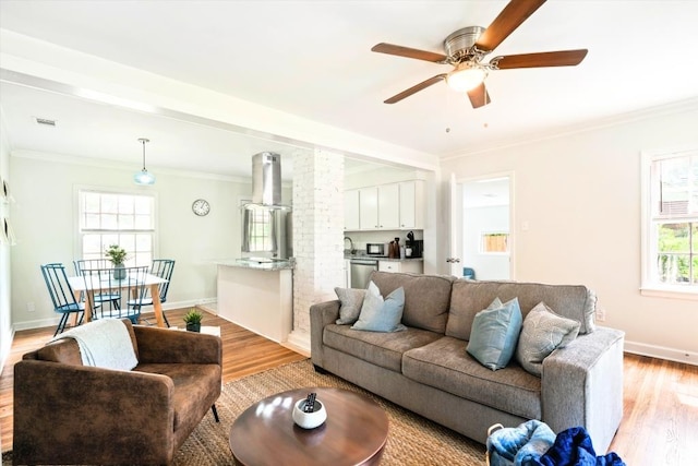 living room featuring ceiling fan, ornamental molding, and light hardwood / wood-style floors