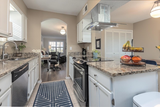 kitchen with appliances with stainless steel finishes, white cabinets, island exhaust hood, and sink