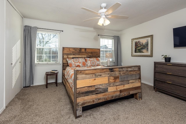 bedroom featuring ceiling fan, light carpet, and a textured ceiling