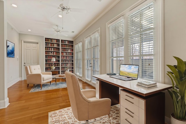 office area featuring ceiling fan, a wealth of natural light, built in shelves, and light hardwood / wood-style flooring