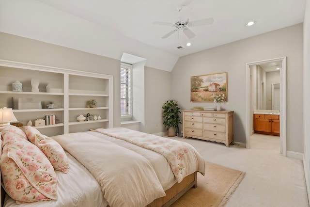 bedroom with vaulted ceiling, ensuite bathroom, light colored carpet, and ceiling fan