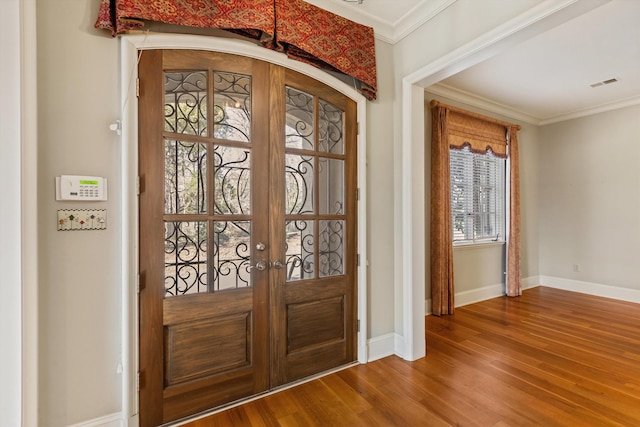 entrance foyer with ornamental molding, french doors, and hardwood / wood-style floors