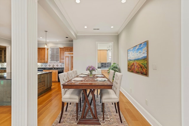 dining room featuring light wood-type flooring and crown molding