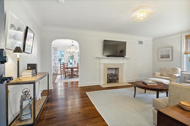 living room with a tile fireplace, a notable chandelier, crown molding, and dark hardwood / wood-style floors