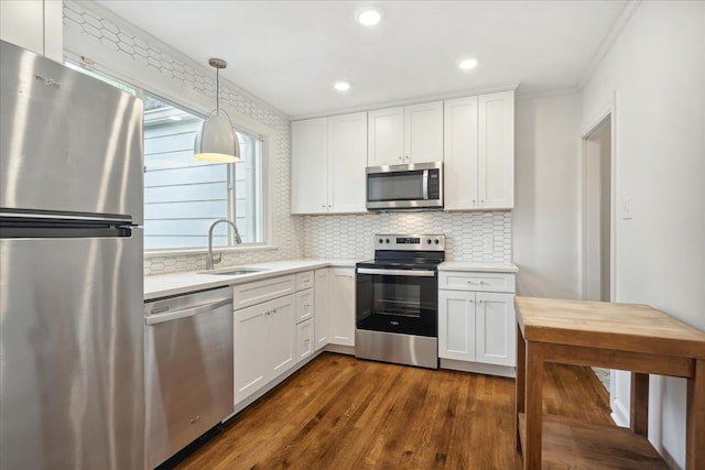 kitchen featuring sink, appliances with stainless steel finishes, decorative light fixtures, white cabinets, and dark wood-type flooring