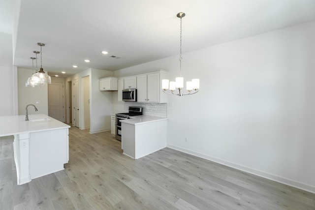 kitchen featuring appliances with stainless steel finishes, sink, white cabinetry, decorative light fixtures, and tasteful backsplash