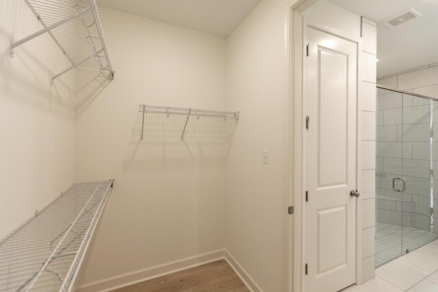 walk in closet with light hardwood / wood-style flooring