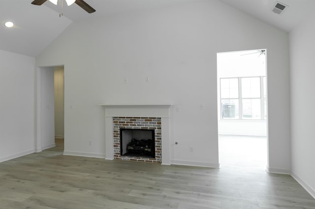 unfurnished living room featuring a brick fireplace, ceiling fan, vaulted ceiling, and light hardwood / wood-style flooring