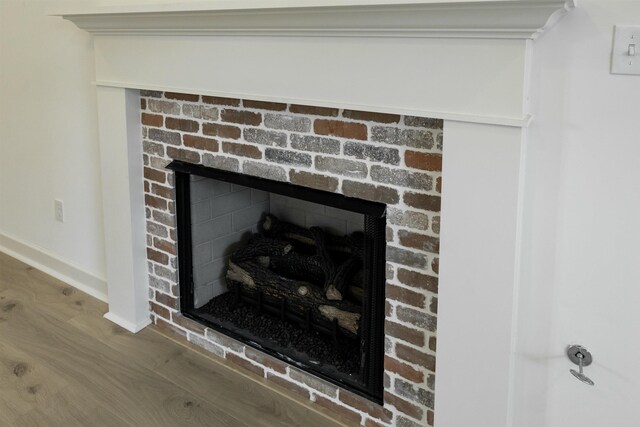 details with a brick fireplace and hardwood / wood-style flooring