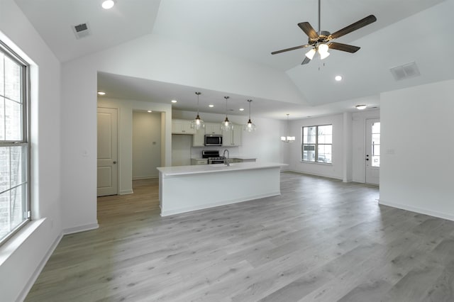 kitchen featuring light hardwood / wood-style flooring, pendant lighting, a kitchen island with sink, white cabinets, and appliances with stainless steel finishes