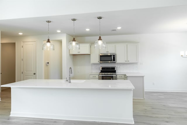 kitchen with sink, stainless steel appliances, an island with sink, and white cabinets