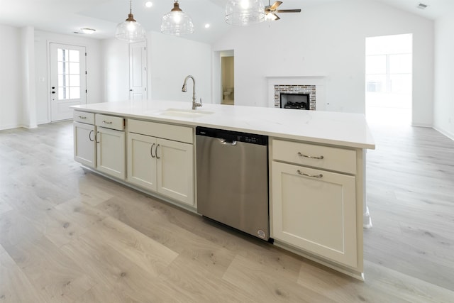 kitchen featuring dishwasher, vaulted ceiling, light stone counters, sink, and decorative light fixtures