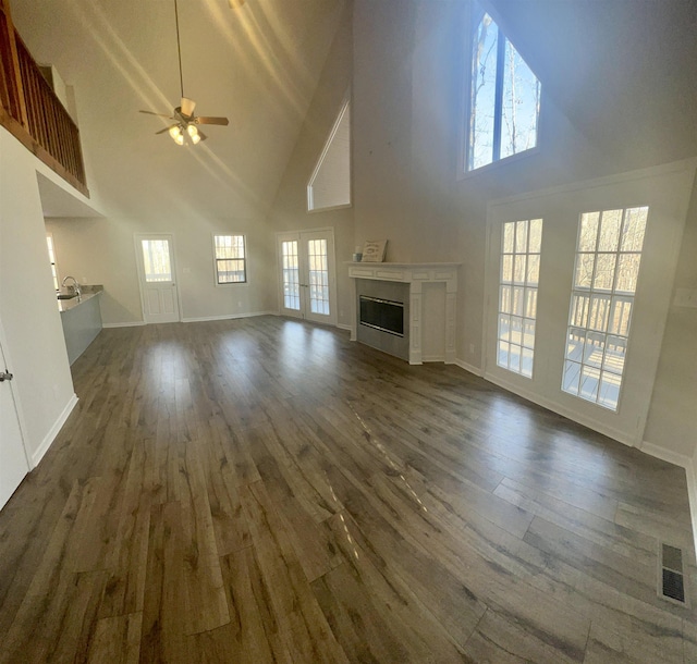 unfurnished living room with ceiling fan, dark hardwood / wood-style flooring, and a towering ceiling