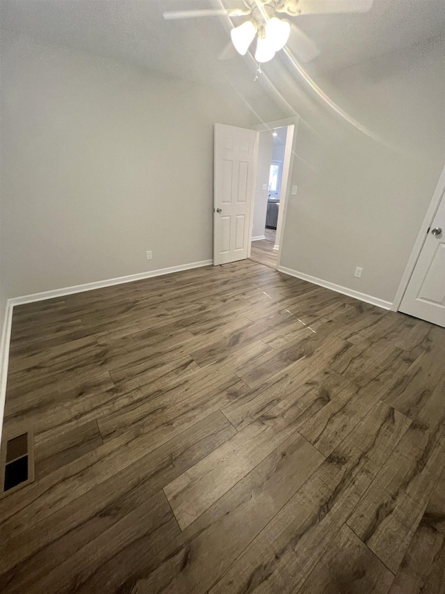 empty room with ceiling fan, dark wood-type flooring, and vaulted ceiling