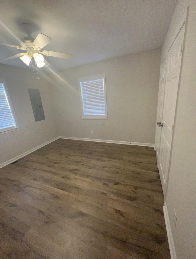 unfurnished room with electric panel, dark wood-type flooring, and ceiling fan