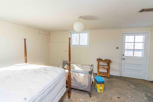 bedroom with a textured ceiling and concrete flooring