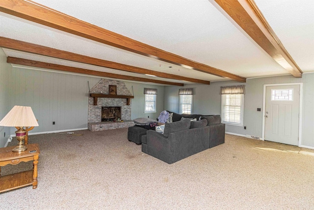 carpeted living room with a fireplace, a textured ceiling, and beamed ceiling