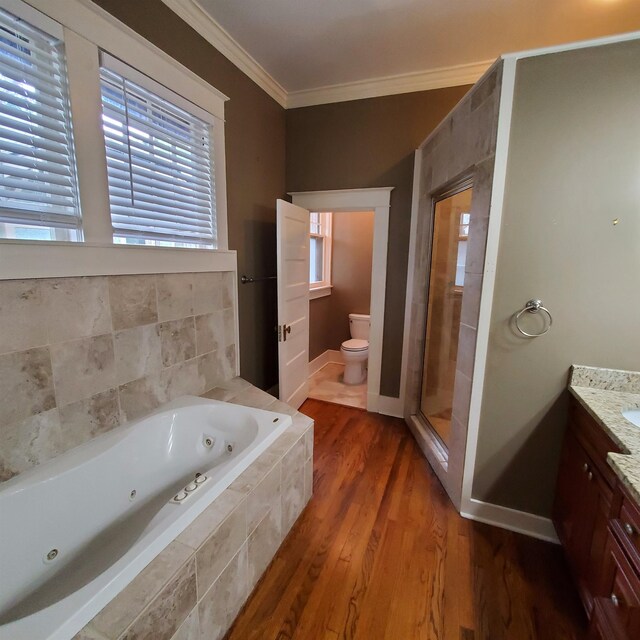 full bathroom with toilet, hardwood / wood-style floors, ornamental molding, independent shower and bath, and vanity