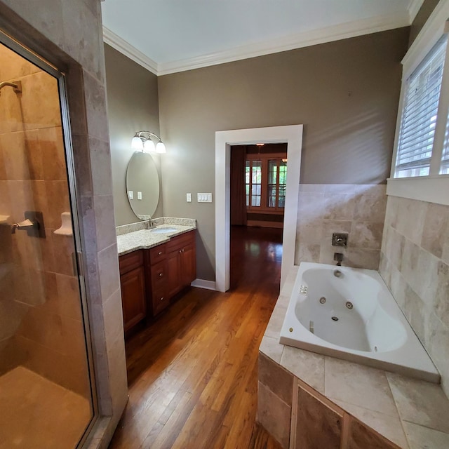 bathroom featuring a healthy amount of sunlight, ornamental molding, separate shower and tub, wood-type flooring, and vanity