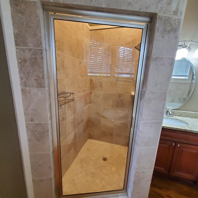 bathroom featuring a shower with shower door and vanity