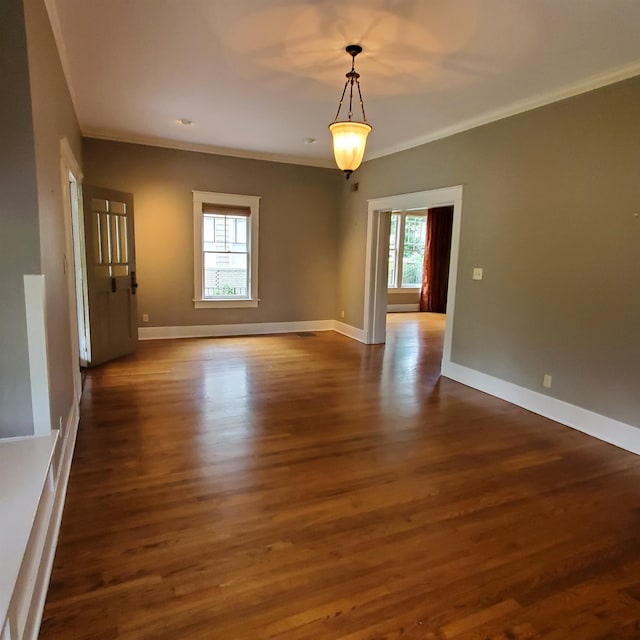 empty room with ornamental molding and dark wood-type flooring