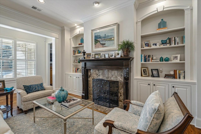 living room featuring hardwood / wood-style flooring, a premium fireplace, built in features, and ornamental molding