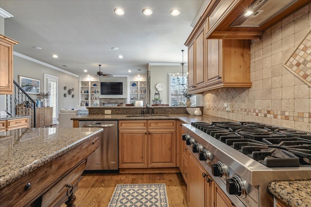 kitchen with light wood-type flooring, stone countertops, crown molding, appliances with stainless steel finishes, and sink