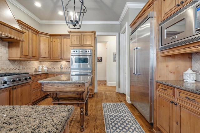 kitchen featuring pendant lighting, light stone counters, and appliances with stainless steel finishes