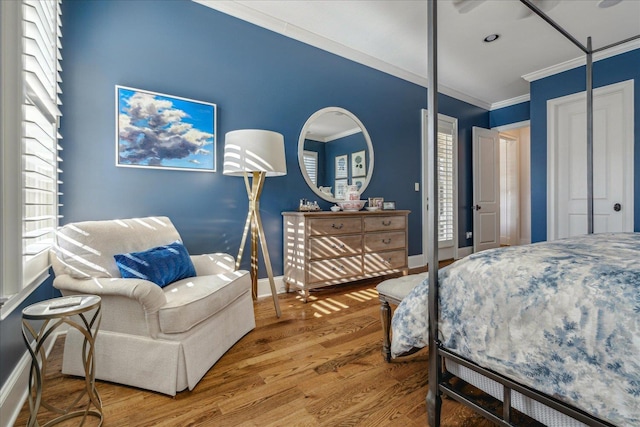 bedroom featuring multiple windows, a closet, hardwood / wood-style floors, and ornamental molding