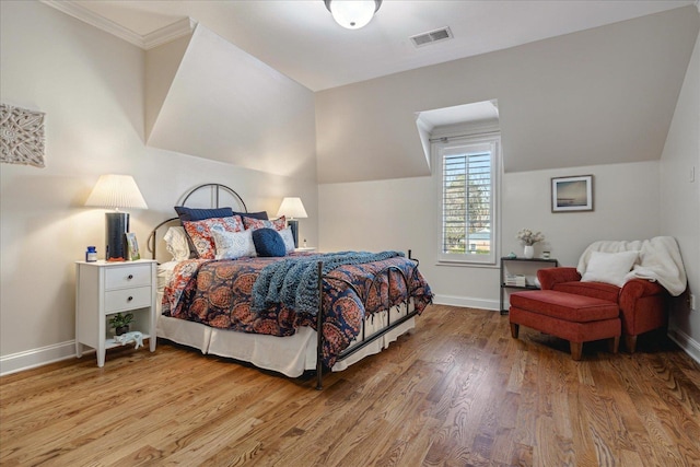 bedroom featuring vaulted ceiling, ornamental molding, and light hardwood / wood-style flooring