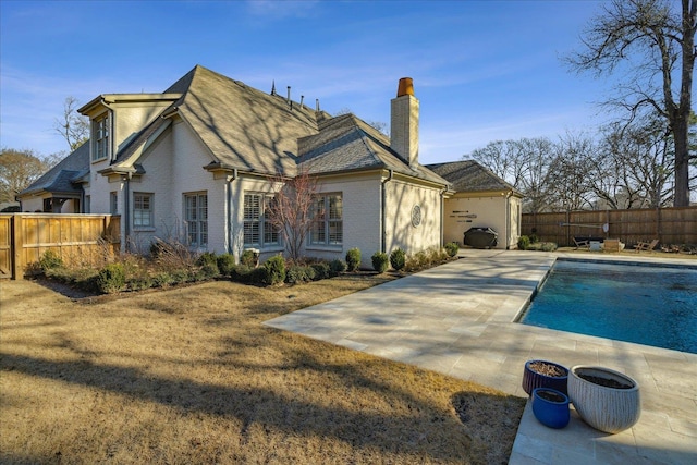 rear view of house with a patio, a lawn, and a fenced in pool