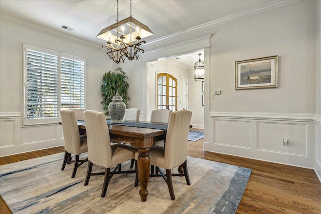 dining area with wood-type flooring, a chandelier, and ornamental molding