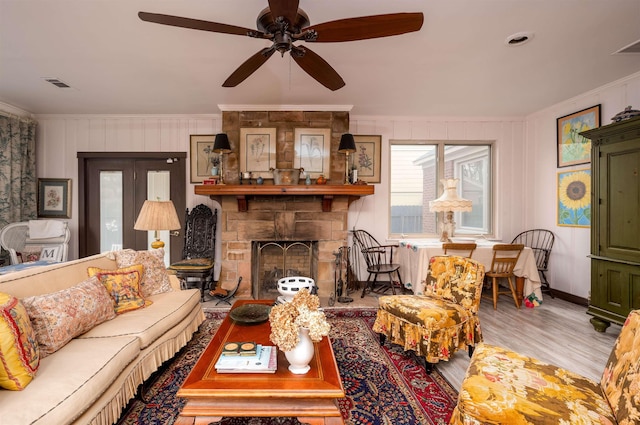 living room with ceiling fan, hardwood / wood-style floors, crown molding, and a fireplace