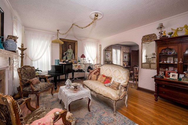 living area with a textured ceiling, a high end fireplace, ornamental molding, and hardwood / wood-style floors