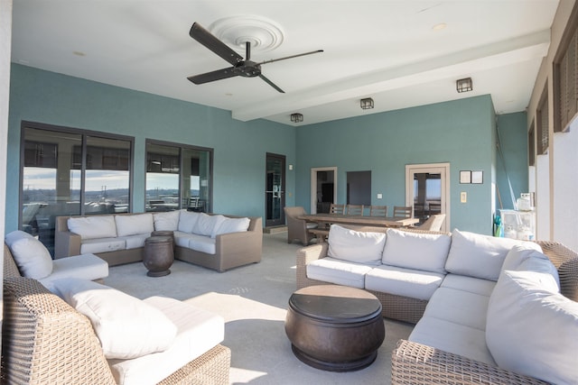 living room featuring beam ceiling, ceiling fan, and light carpet