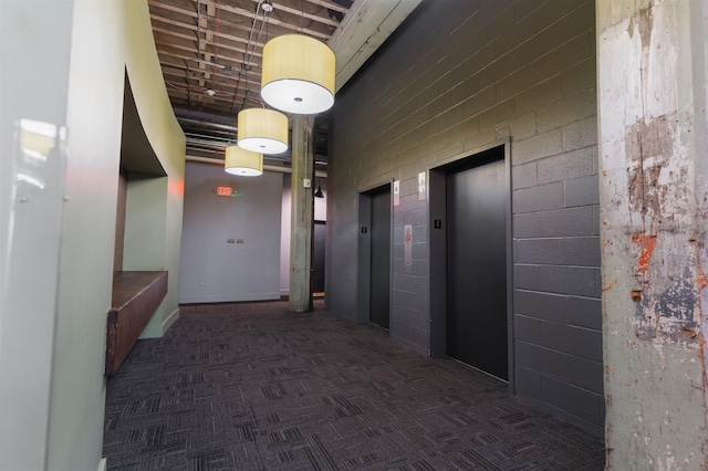 corridor with elevator and dark carpet