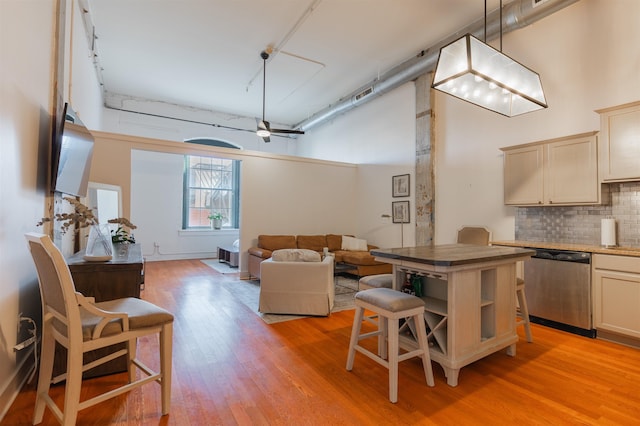 kitchen with a towering ceiling, dishwasher, backsplash, and decorative light fixtures