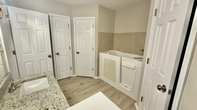 bathroom featuring a textured ceiling, a bathing tub, wood-type flooring, and vanity